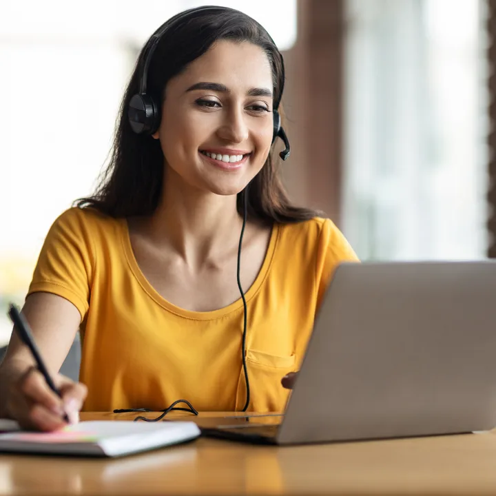 A student taking notes while listening to her tutor